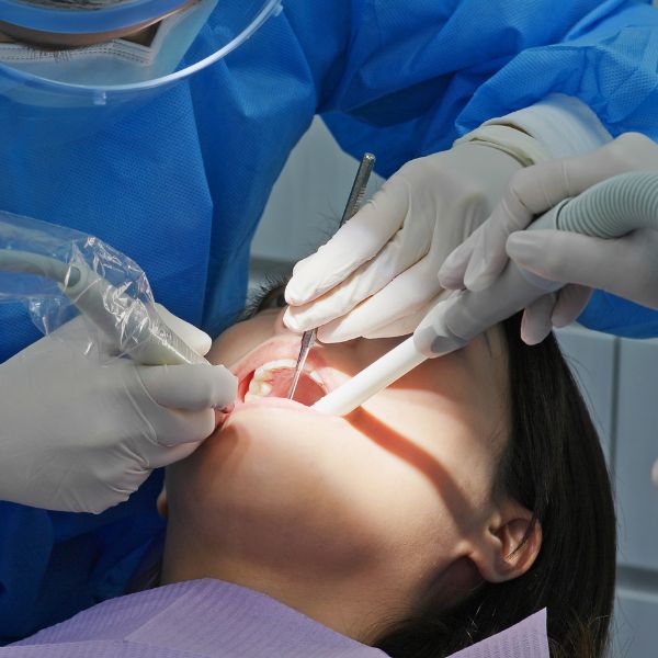 A dentist and assistant working on a patient’s tooth with suction in place
