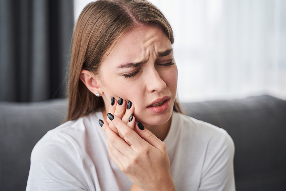 A woman holding her cheek with a painful toothache