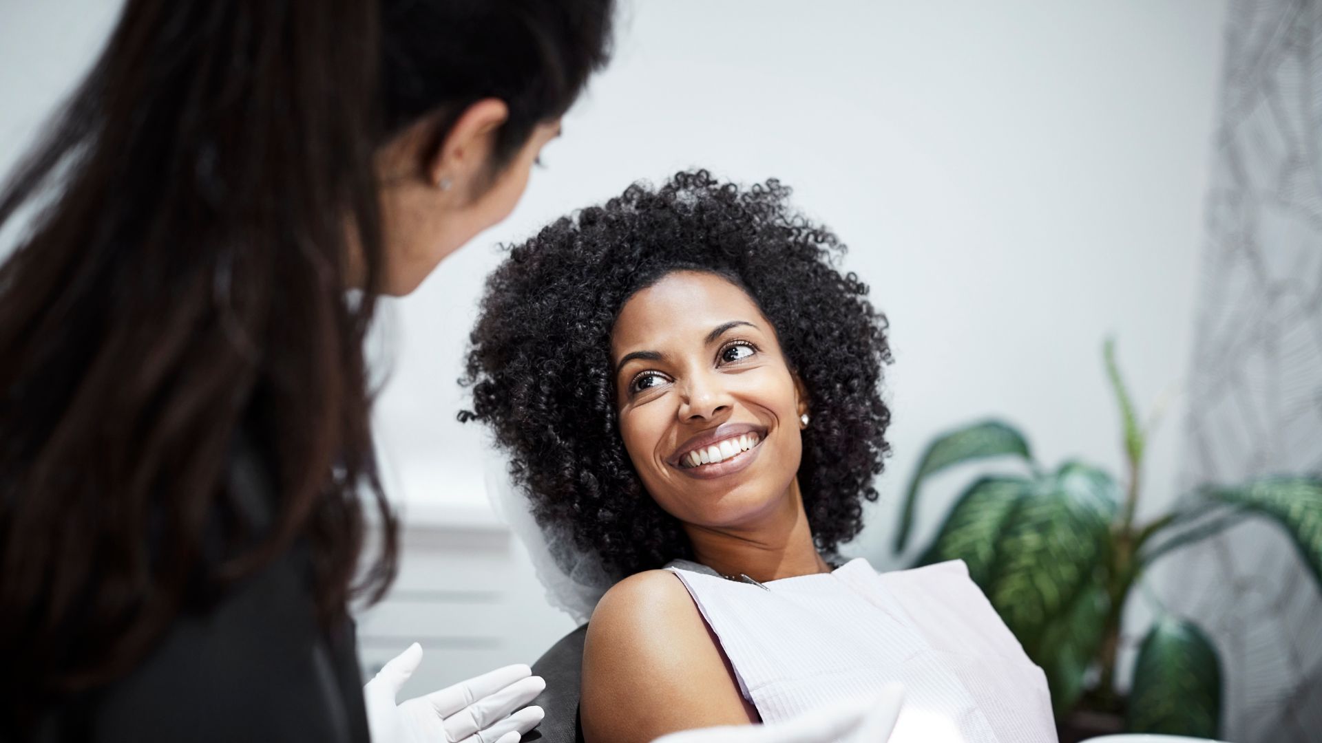 Patient smiling during dental appointment, dentist nearby.