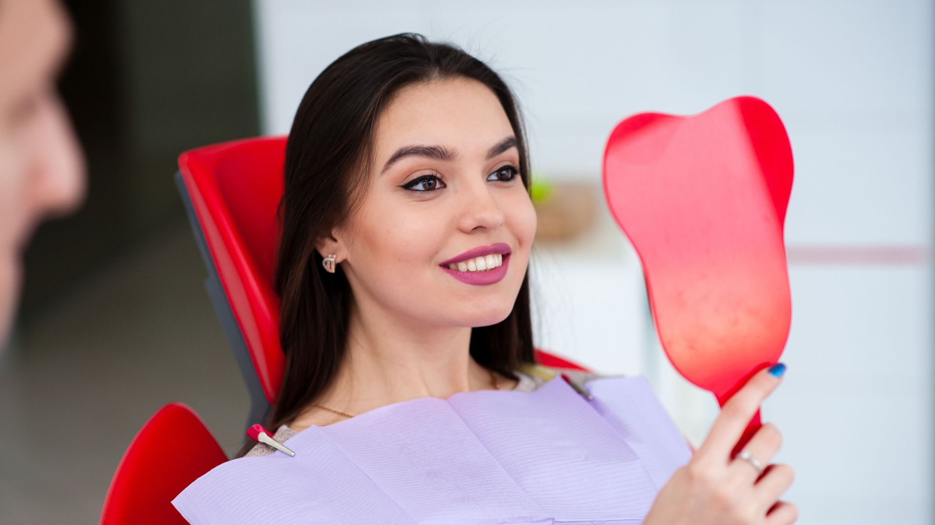 Woman smiling with red hand mirror.