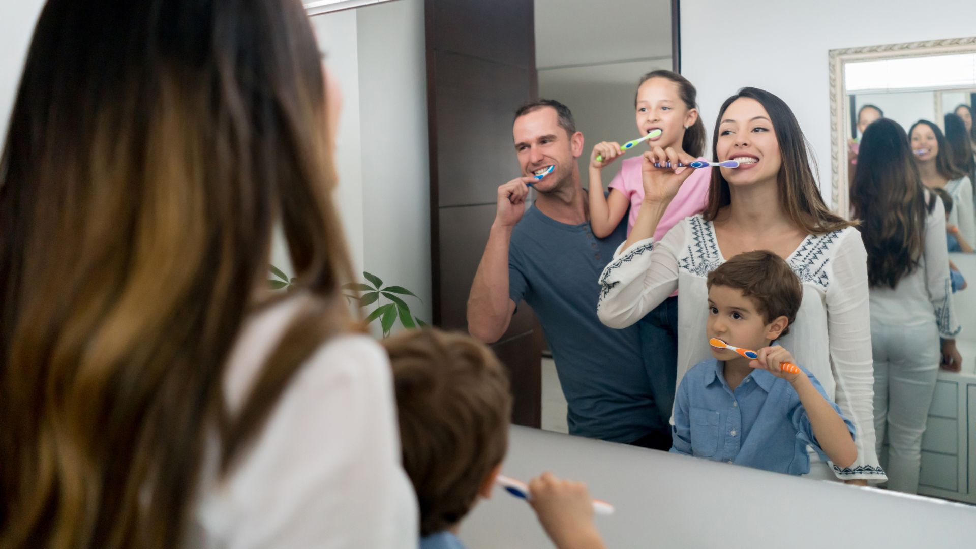 Family brushing teeth together in bathroom.