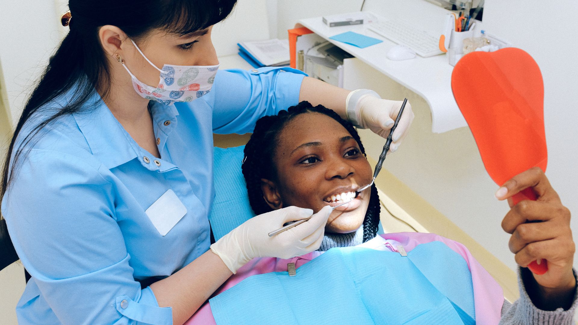 Dentist examining patient holding a red mirror.