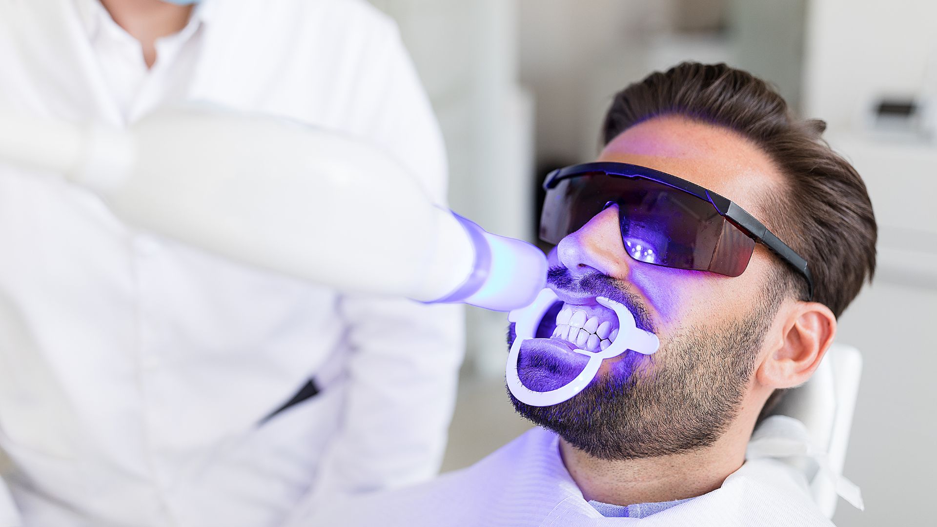 Man receiving professional teeth whitening treatment.