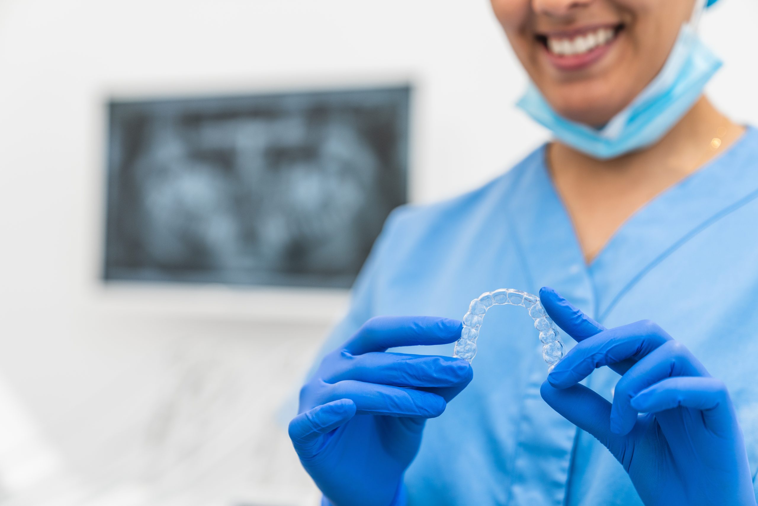Dental hygienist holding a clear aligner tray in a treatment room