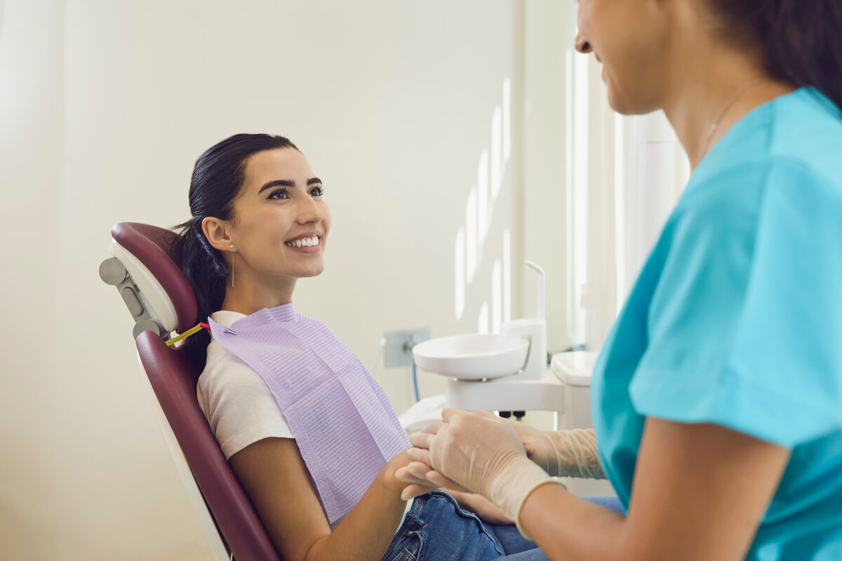 A dental assistant reassuring a smiling patient in the treatment chair