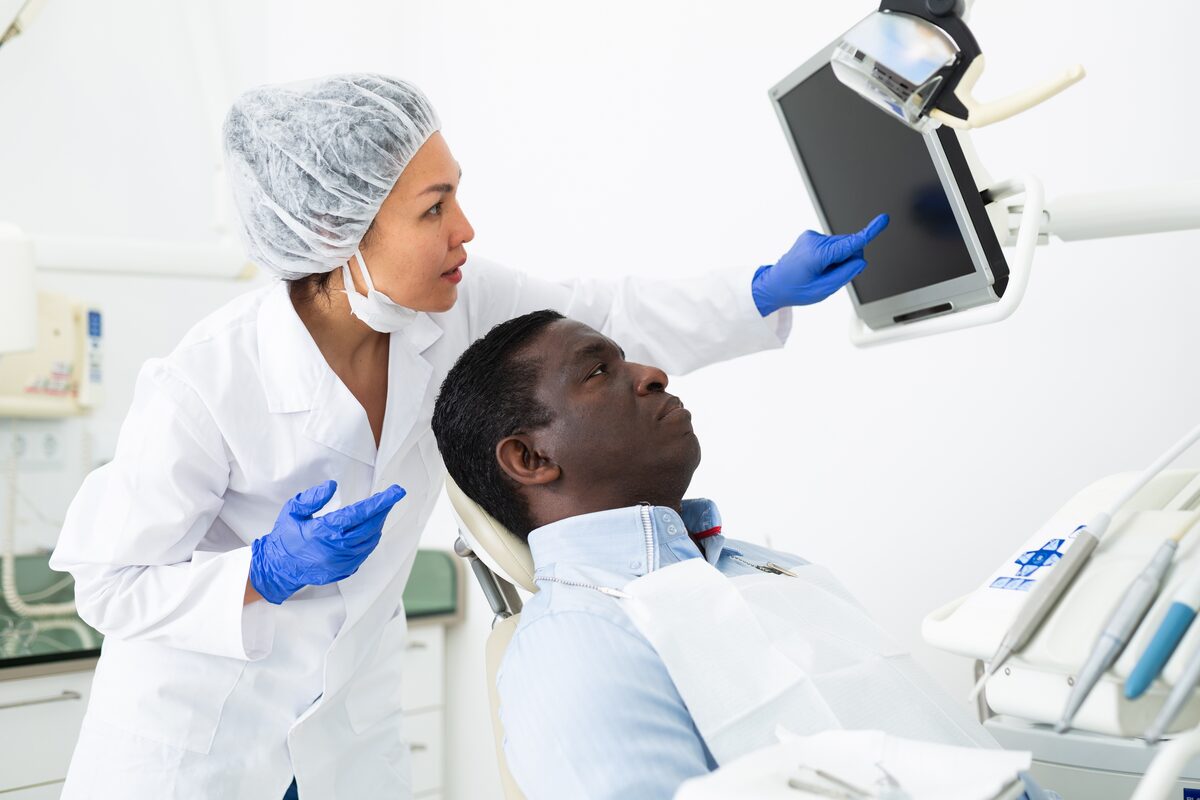 Dentist showing a patient his dental x-ray on a monitor during an emergency visit