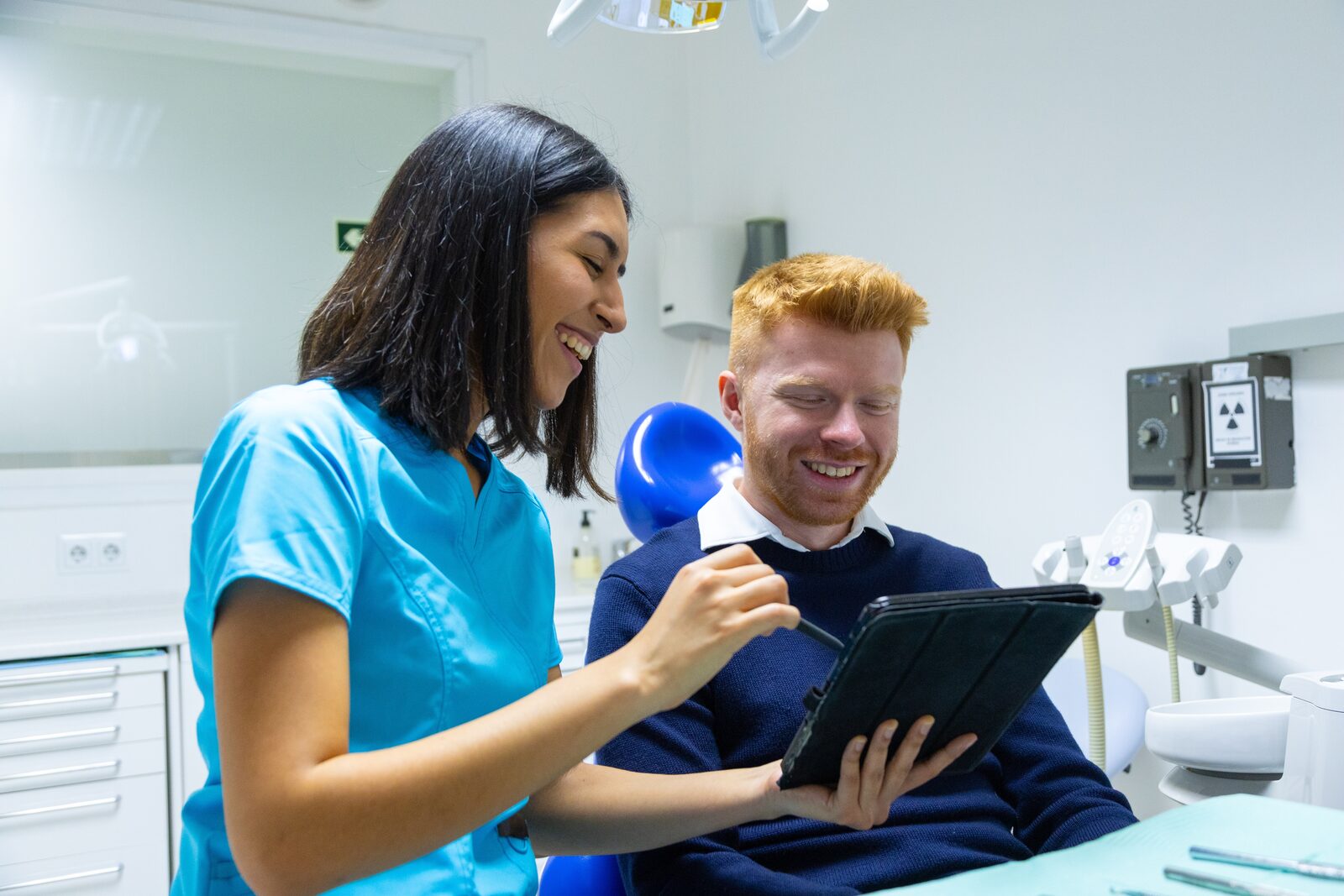 Dental team member reviewing a treatment plan on a tablet with a smiling patient