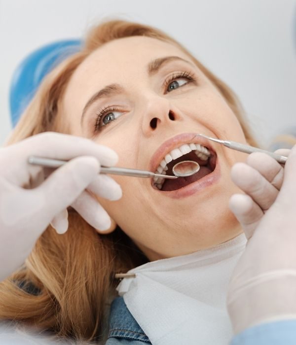 Dentist examining a patient’s teeth and gums with a mirror and probe